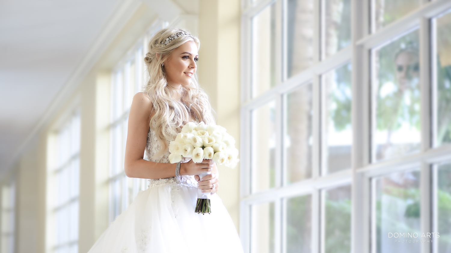 bride holding flowers by window on wedding day Aventura Turnberry