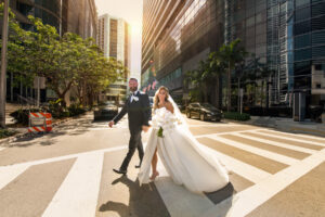 Photojournalistic portrait of Bride & groom walking across the street in Downtown Miami by Domino Arts Photography